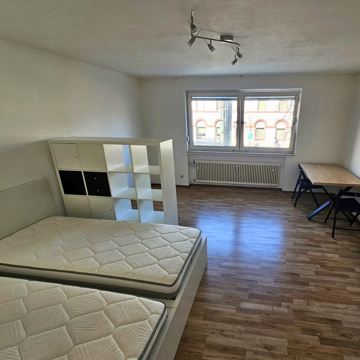 Möblierter Wohn-/Schlafbereich mit Regal, Doppelbett und Schreibtisch