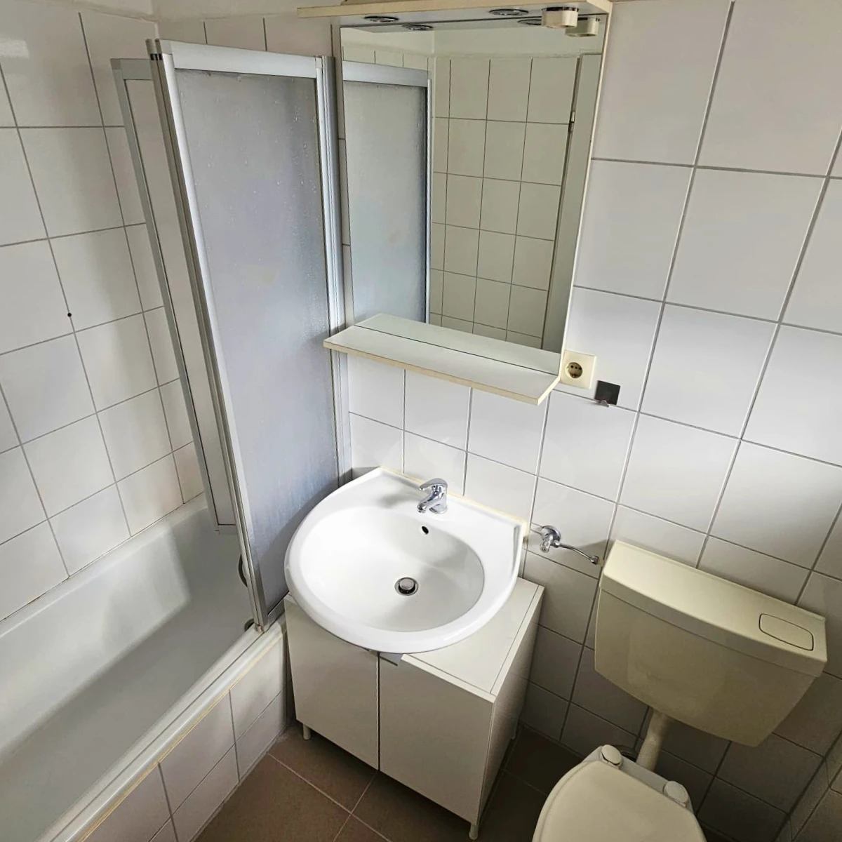 Badezimmer mit Badewanne, Duschabtrennung, Waschbecken und WC