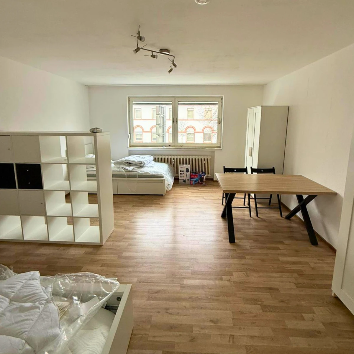 Wohnbereich mit Regal, Kleiderschrank, Esstisch und Bett